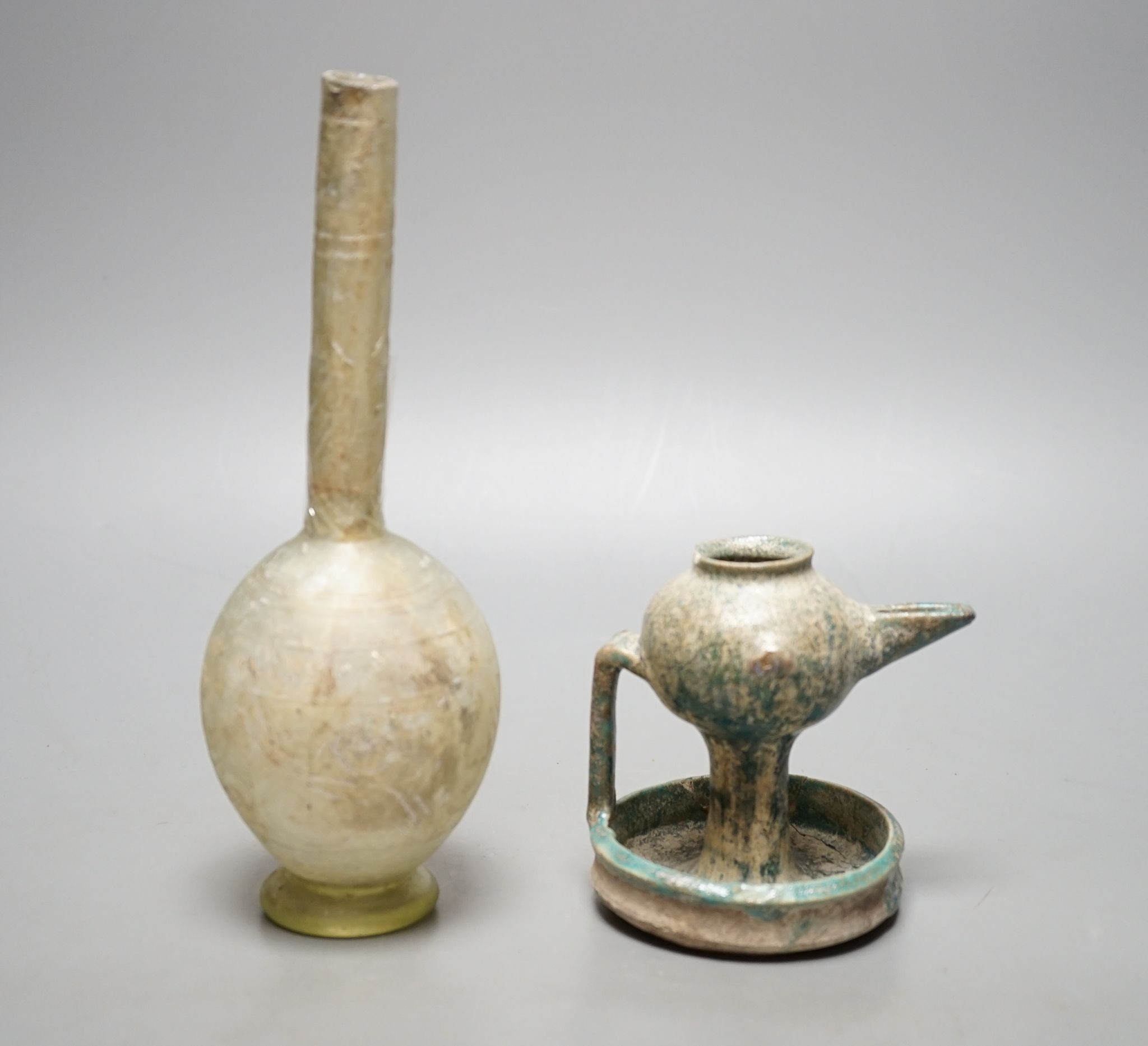 A Kashan oil lamp, 13th/14th century, and an early Islamic glass bottle., Bottle 22 cms high.